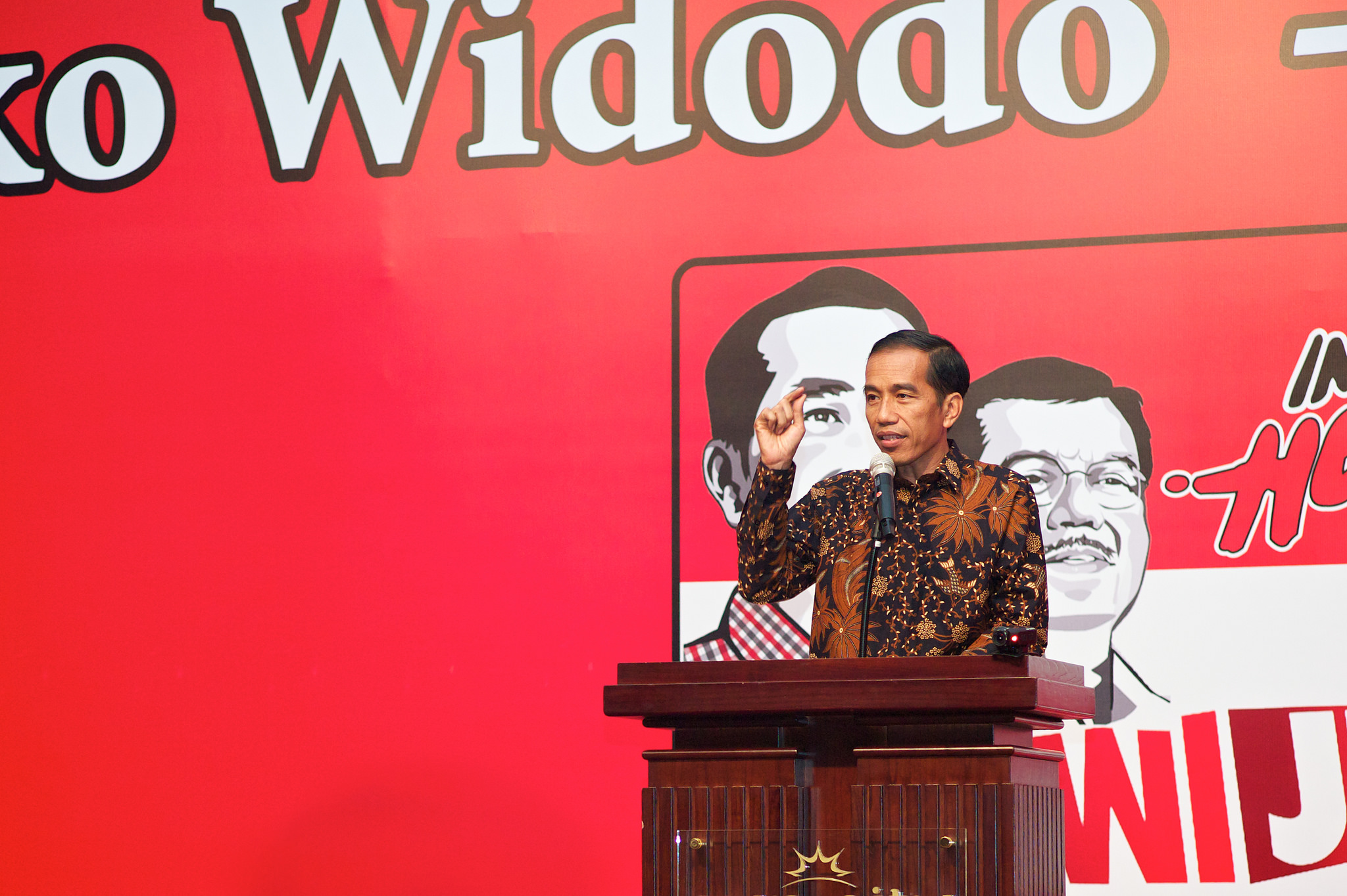 After giving the export ban strong support in 2014, Jokowi reversed it in 2017. (Hendrik Mitarno) President Joko Widodo speaks at a podium, with a red banner as a backdrop.